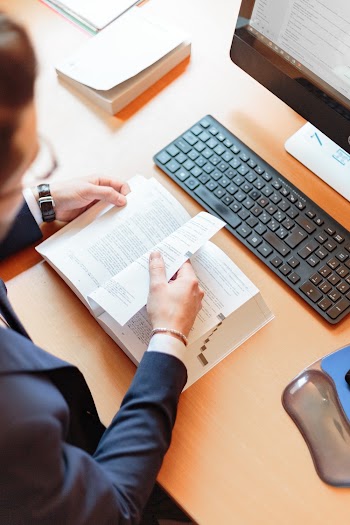 Man Reading Book Beside Computer Keyboard