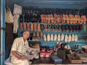 Man Reading Newspaper Surrounded by Shoes