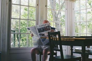 man reading newspaper while sitting on chair