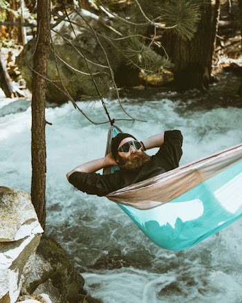 man reclining on blue and brown hammock