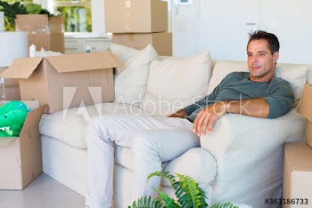 Man resting on sofa surrounded with moving boxes