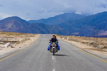 Man Riding a Motorcycle Passing by a Concrete Road