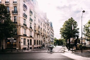 man riding bike on middle of road near white concrete building