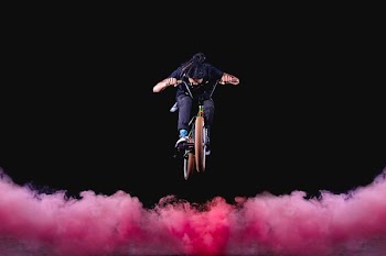 man riding BMX bike performing stunts with red fogs