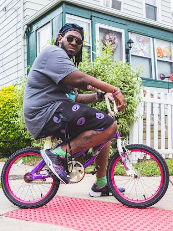 Man Riding Purple Bicycle Near White Fence