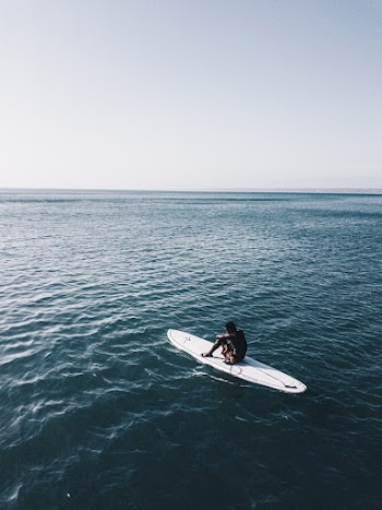 Man Riding White Surfboard In The Middle Of Ocean