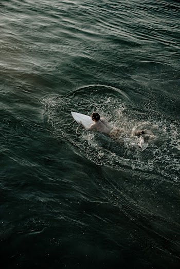 Man Riding White Surfboard on Body of Water