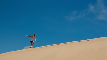 man running on brown sand under blue sky