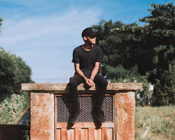 Man Seated on Concrete Pavement Looking Sideways