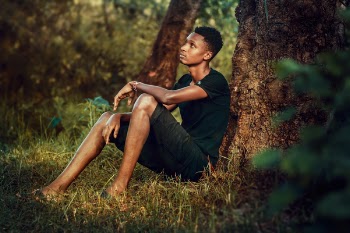 Man Seating Beside Tree Trunk