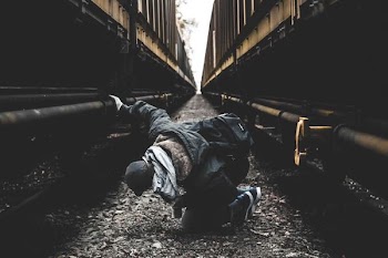 man seating on ground in-between of two brown metal walls