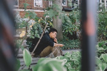 Man Seating Outdoor Beside Green Leafed Plants