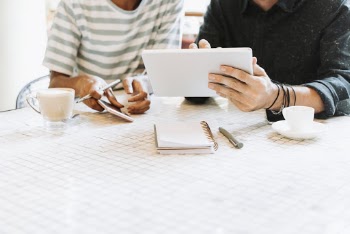 Man Showing His Laptop on Woman While Sitting Beside Table Inside Room