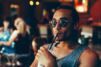 man sipping cooler while sitting on chair
