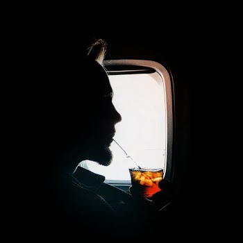 man sipping drink beside window