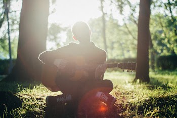 Man Siting on Grass While Playing Guitar