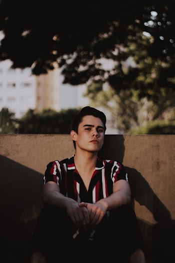 Man Sitting and Leaning on Rail