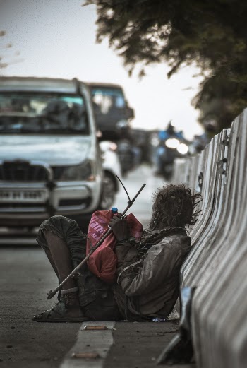 Man Sitting at the Side of the Road Leaning Back on Road Railing Near Cars during Day