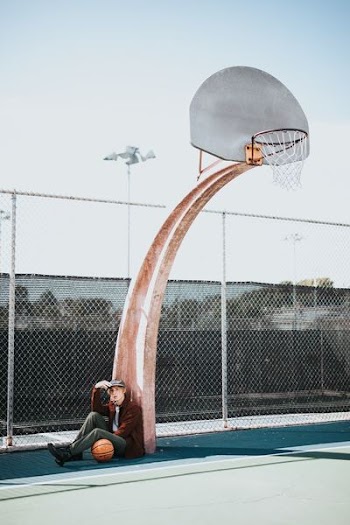 man sitting beside basketball hoop