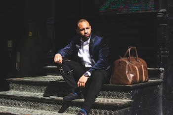 Man Sitting Beside Brown Leather Duffel Bag
