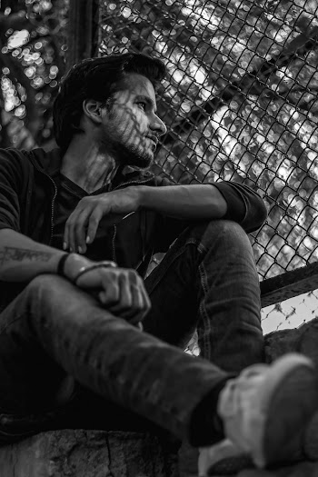 Man Sitting Beside Chain-Link Fence