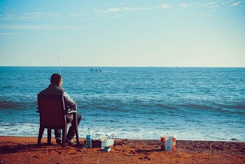 Man Sitting in a Chair Near Sea Shore