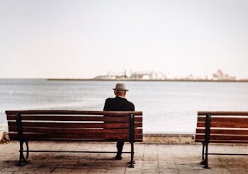 man sitting in brown wooden bench