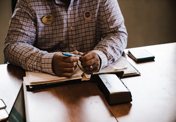 Man Sitting In Front Of Table Holding Blue Marker