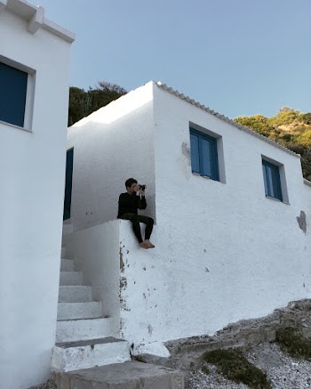 Man Sitting Near White Building