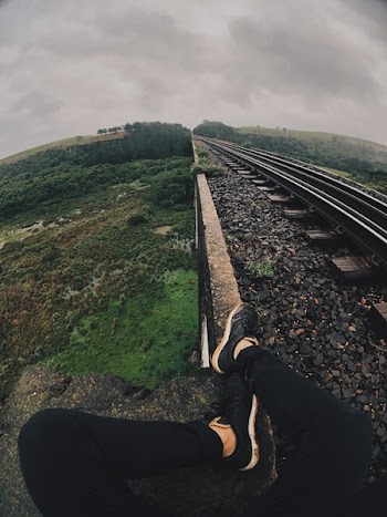 Man Sitting Next to the Railroad Tracks