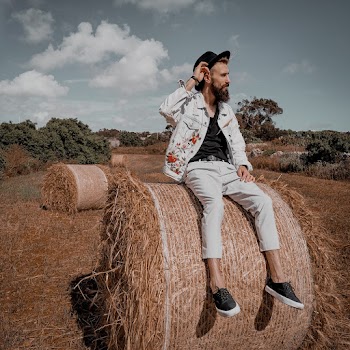 Man Sitting On A Roll Of Hay