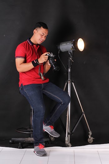 Man Sitting on Bar Chair Holding Camera Beside on Lights With Stand
