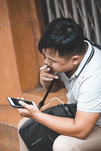 Man Sitting on Bench While Holding Smartphone