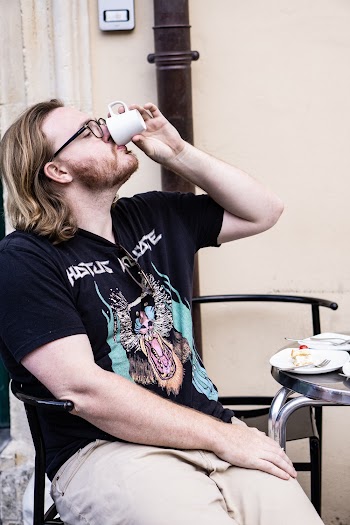 Man Sitting On Black Metal Chair While Drinking