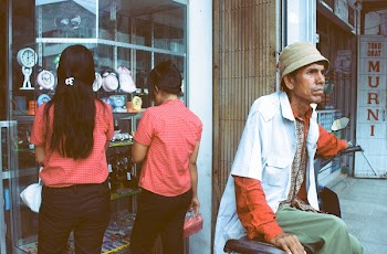 Man Sitting on Black Motorcycle Behind Two Women Looking a Display on Store Front