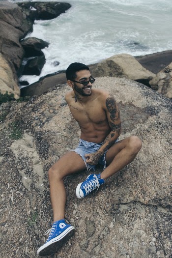 Man Sitting on Boulder Near Body of Water