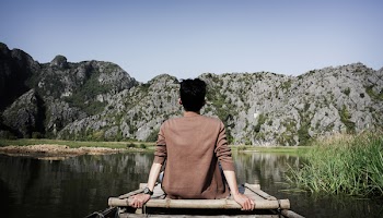 Man Sitting on Bridge Front of Mountain