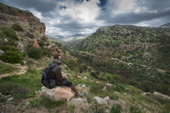 Man Sitting on Brown Boulder Top on Hill