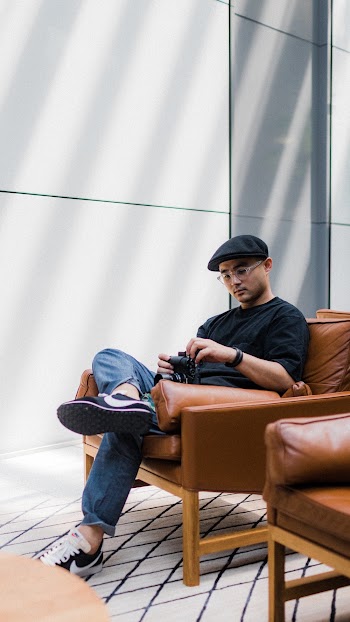 Man Sitting on Brown Leather Padded Armchair Holding A Camera 