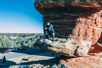Man Sitting on Brown Rock Formation