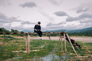 Man Sitting on Brown Wooden Bridge