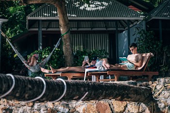 Man Sitting on Brown Wooden Lounger