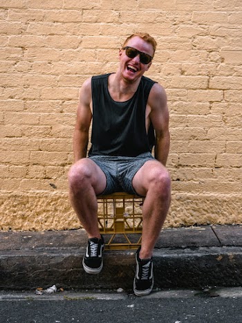 Man Sitting on Chair Beside Brick Wall