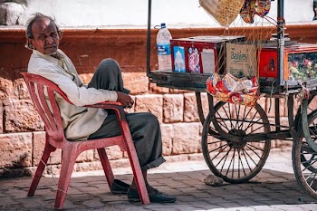 man sitting on chair beside food cart