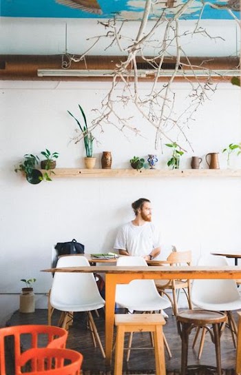 man sitting on chair under wall-mounted shelf inside room
