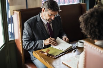 Man Sitting on Chair Writing Holding Notebook and Pen