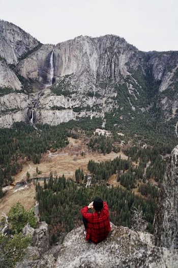 man sitting on cliff during daytime