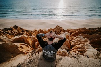 man sitting on clip of rock mountain