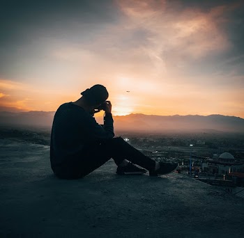 Man Sitting On Concrete Ground