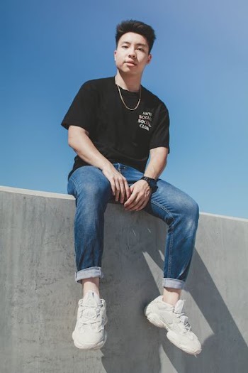 man sitting on concrete pavement under clear blue sky during daytime